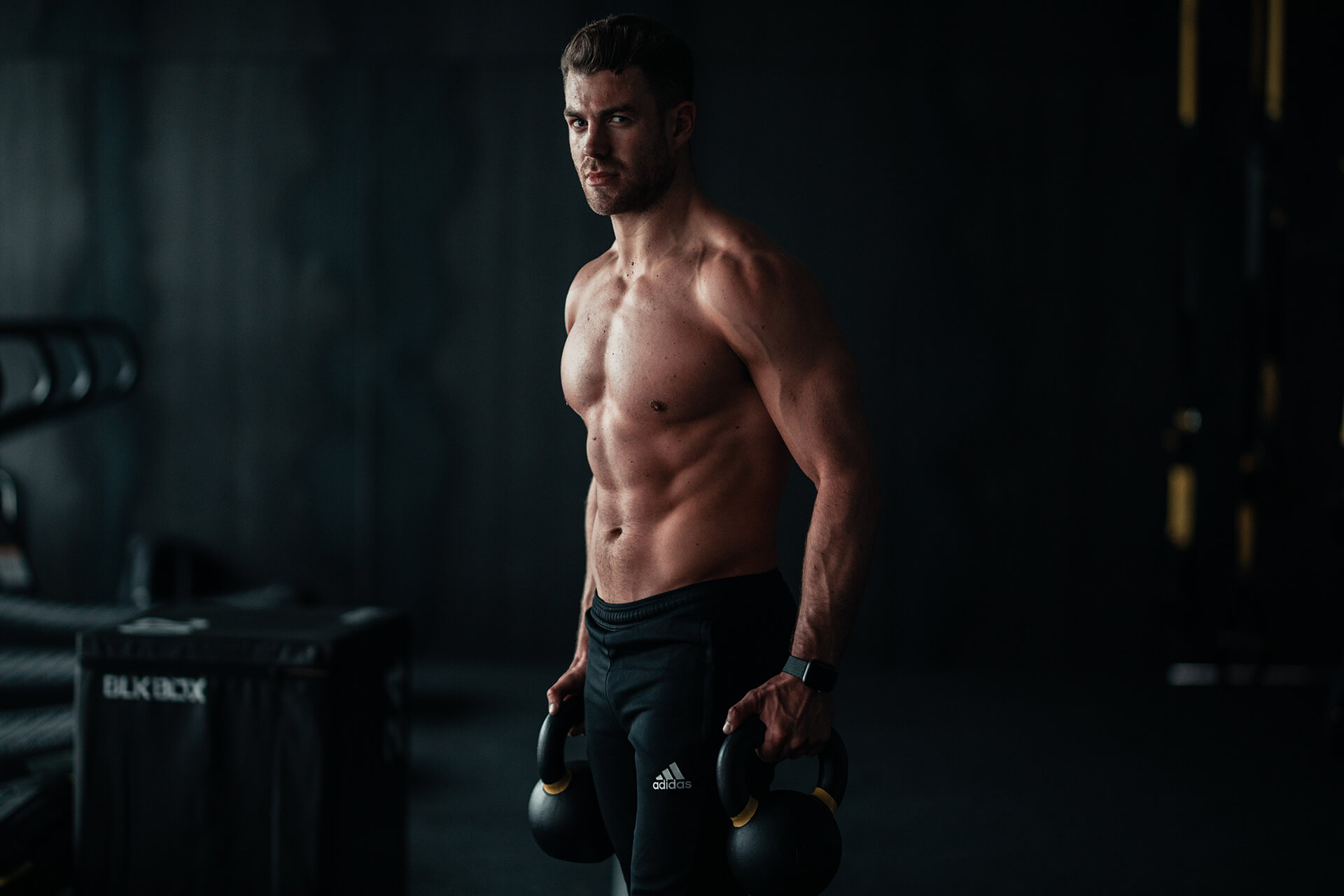 Image of a fit male holding weights inside a fitness gym